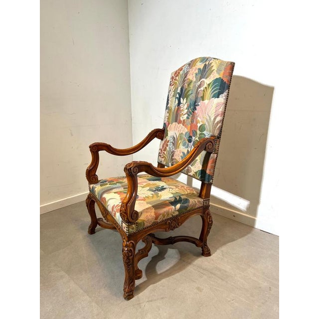 Elegant vintage armchair in Louis XV style, featuring beautifully carved wooden details and a richly patterned floral...