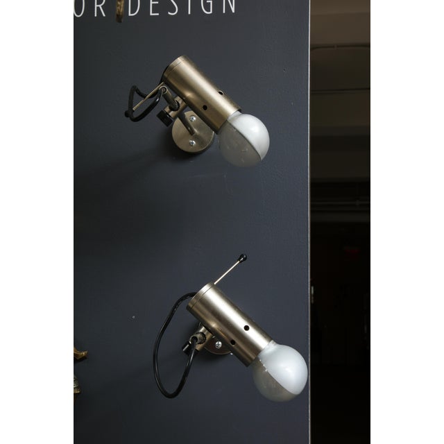 Sleek minimalist pair of nickel-plated bronze wall sconces or bedside lights, by Tito Agnoli for Oluce, 1960s. The shade...