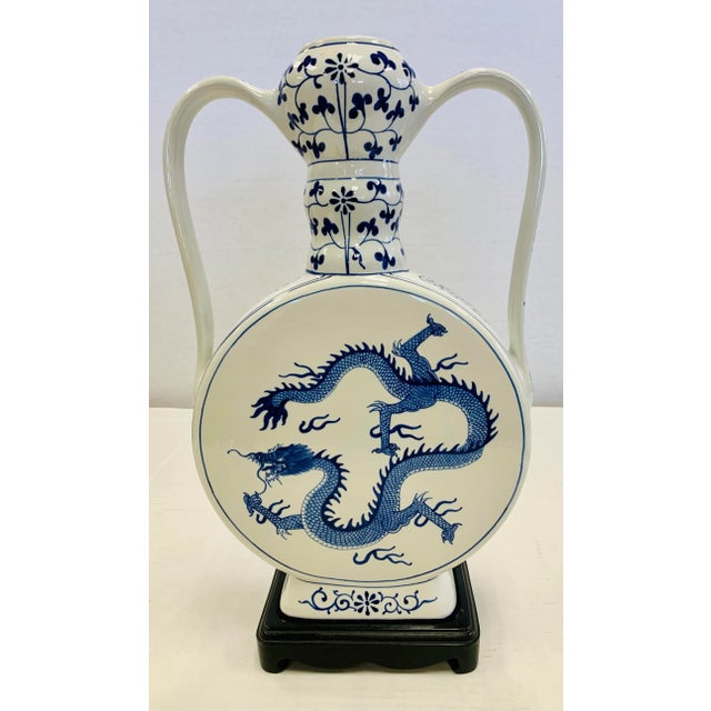 Uniquely shaped tall blue and white porcelain urn has a round body with a long neck and handles. It features a handpainted...