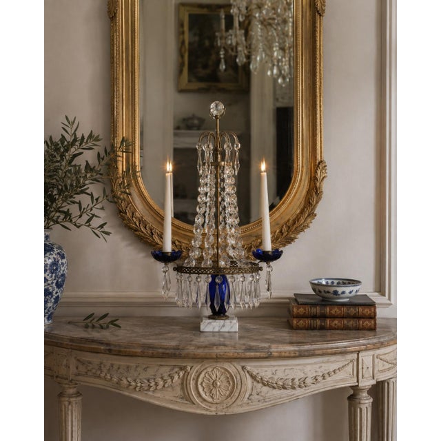 An elegant early 20th century Gustavian-style girandole combining aged brass, cobalt blue glass, clear faceted crystal,...
