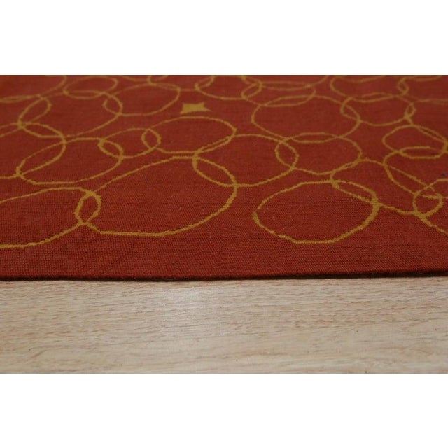 This wool flat weave rug features a primary red and rust color palette suitable for a variety of interior themes. Designed...
