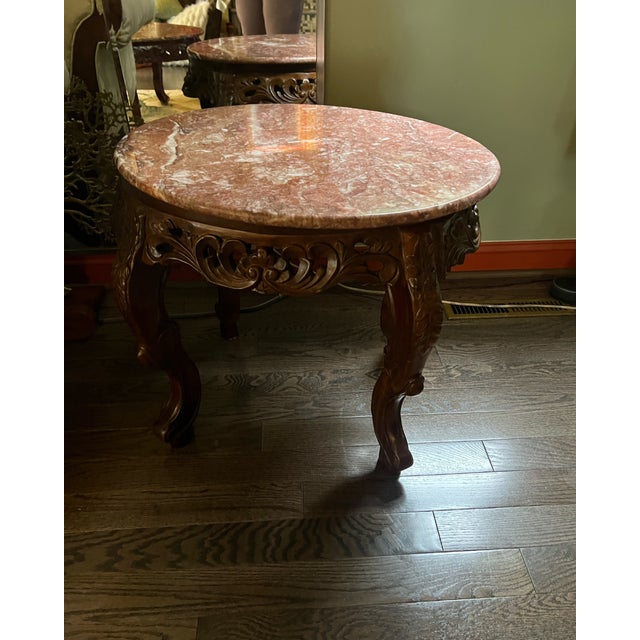 Elegant vintage marble-top end table featuring a richly veined solid marble slab supported by an intricately hand-carved...