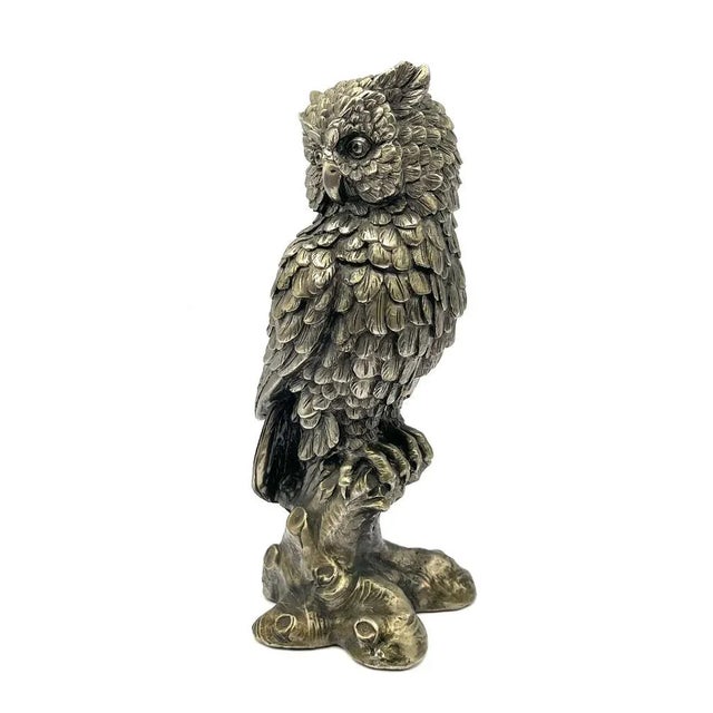 This detailed sculpture depicts an owl perched on a lifelike tree trunk. The surface is carefully modeled, emphasizing the...
