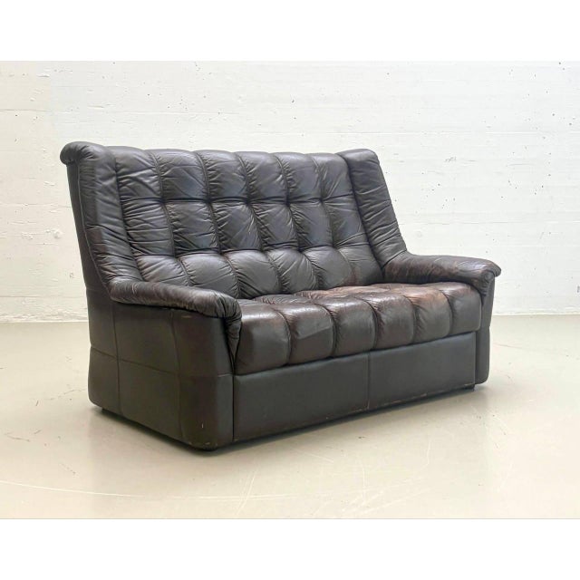 A generously sized vintage leather sofa in dark brown leather, dating from the late 1970s. The design exemplifies the...