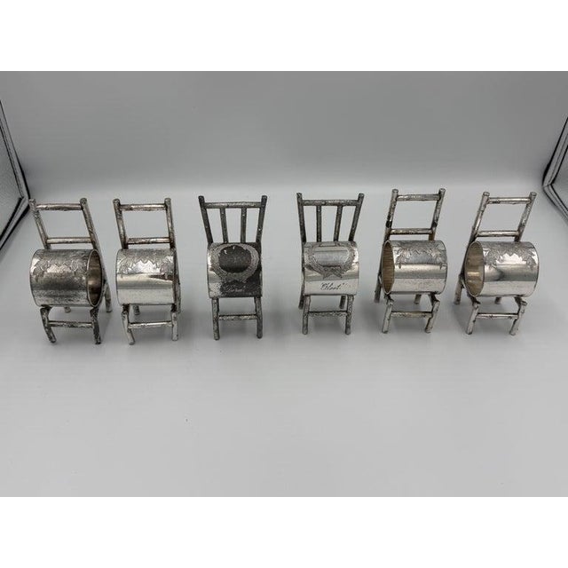 A rare and whimsical set of six silver plated figural napkin rings, each masterfully crafted in the form of a rustic twig...