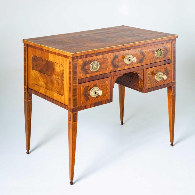 Small ladies' desk with three drawers and large gilt bronze fittings on the front. The desk stands on high pointed legs...
