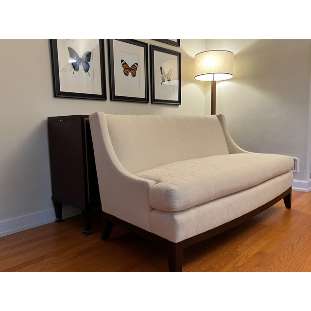 Offering the "Starlet" settee, designed by Barbara Barry for Henredon Furniture. Upholstered in cream fabric with a...