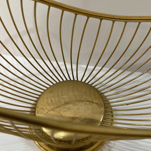 vintage mid-century Italian gold-toned brass wire basket or wine bottle holder featuring an arched handle and a circular...