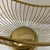 vintage mid-century Italian gold-toned brass wire basket or wine bottle holder featuring an arched handle and a circular...