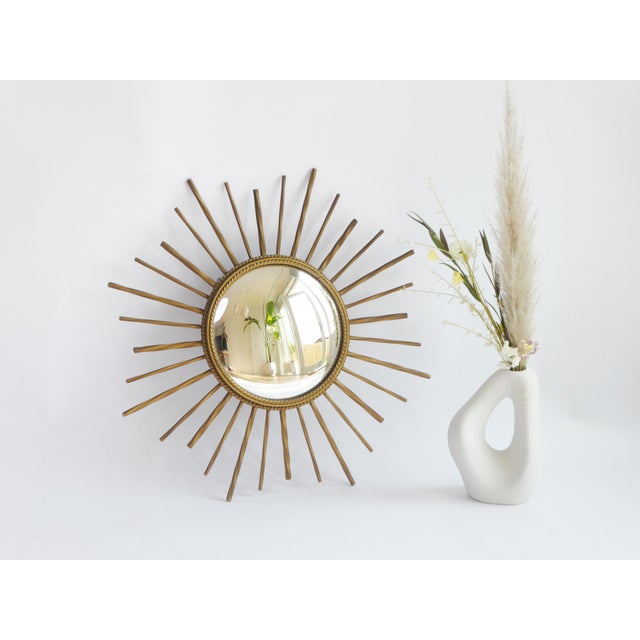 A vintage French sunburst mirror with convex glass and a metal gold gilt frame. The sun mirror has a beautiful framed...