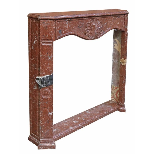 Continental red marble fireplace surround, early 20th c., having molded mantel shelf, over shell carved apron, pilaster...