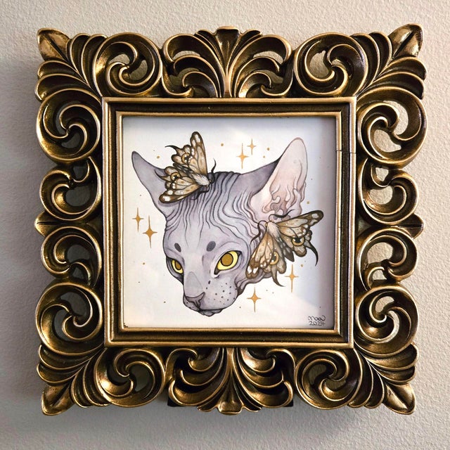 This watercolor artwork features a Sphynx cat, its sleek, hairless form adorned with delicate moths that seem to flutter...