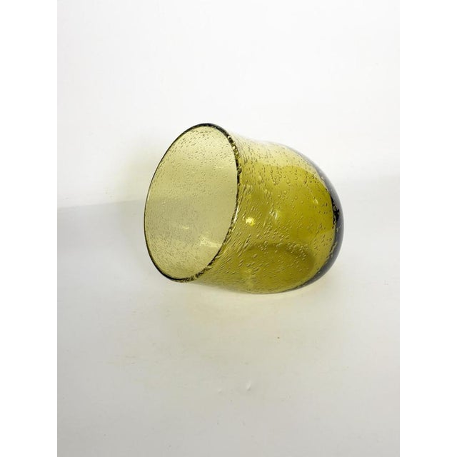 An elegant, Biot-style blown glass catchall, crafted from olive-green tinted glass and characterized by numerous air...