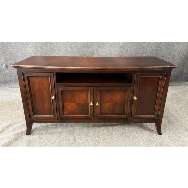 This Stanley Furniture television console cabinet features a gently serpentine front, rich wood tones, and paneled doors...