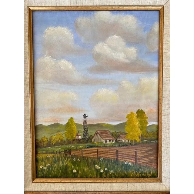 Mid century framed painting of farm landscape with farmhouse, field, and windmill and rolling clouded sky. Painting is...