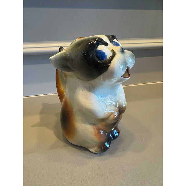 This kitschy but charming cat jug stands 6 1/4 in. high. It has brown and black markings and blue eyes. It's open mouth...