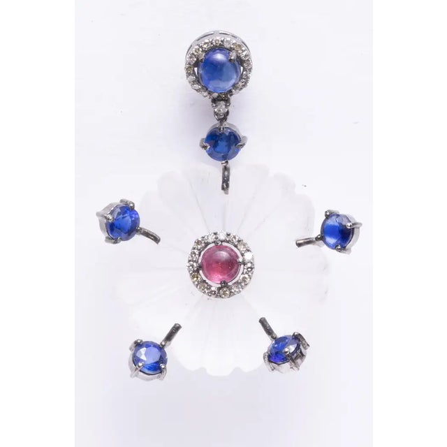 An unusual pair of carved crystal earrings in a floral motif. Features a cabochon pink tourmaline center bordered with...