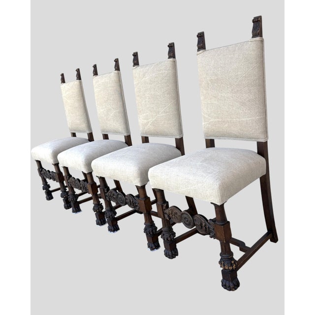 A set of 4 Tudor Revival Dining Chairs. Crinoline style stretchers. Heavily carved front cross-rail with a center "Tudor...