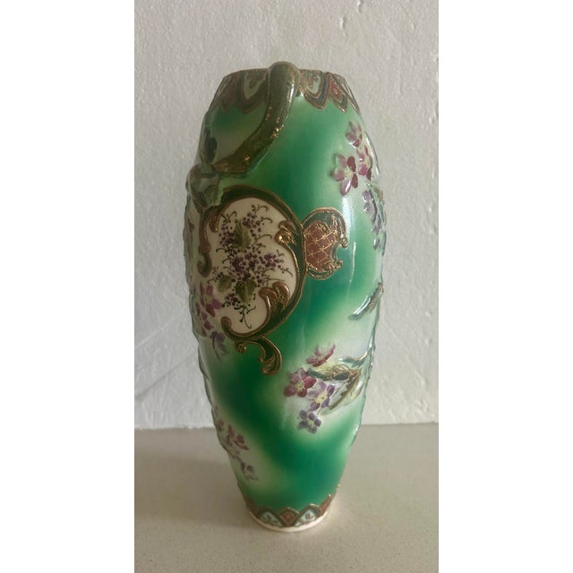This is a vintage Japanese porcelain vase featuring hand-painted floral motifs and raised gold moriage accents on a green-...