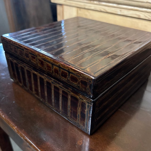 A supremely elegant black lacquer box decorated with delicate gold lines to create an organic linear horizontal pattern....