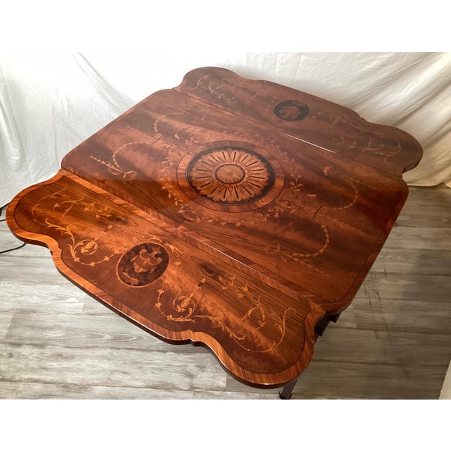 An Italian made highly inlaid Adam style drop leaf table by Rho Mobili. The rich flame mahogany tone with inlay of tulip...