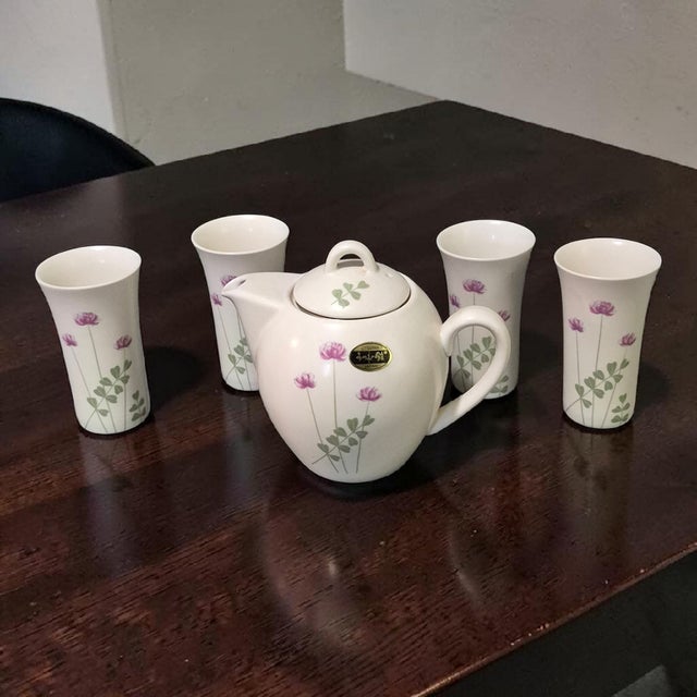 The Japanese Utsuwa Tea Pot & Four Cups with a Pink Wild Flower Pattern is a charming and elegant set perfect for tea...