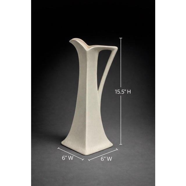 A striking mid-century modern ceramic ewer vase with a tall architectural silhouette and elegant sculptural handle....