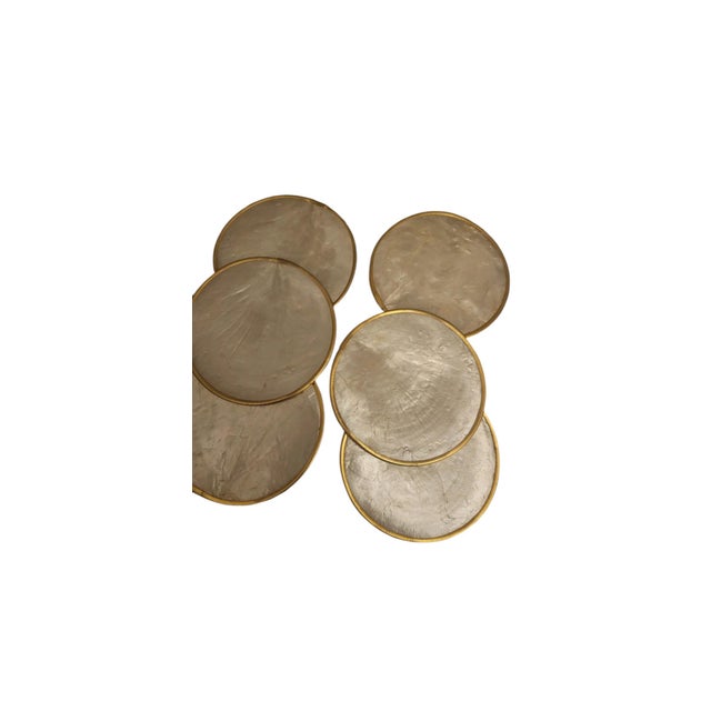 A set of six round capiz shell coasters with brass-tone rims. Capiz shell comes from the windowpane oyster and has been...