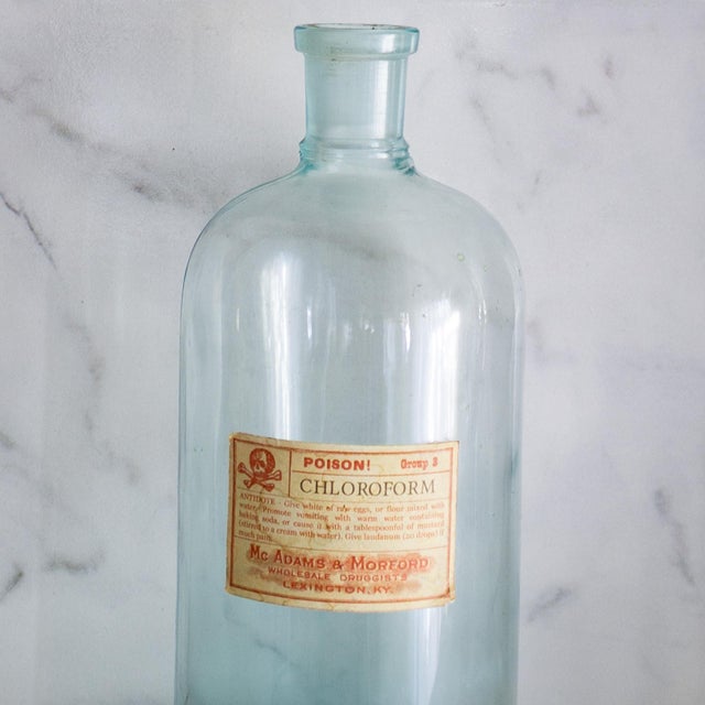 This pair of aqua blue-green glass apothecary bottles each have a unique graphic label that provides a specific age,...