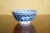 A small Chinese blue-and-white porcelain bowl featuring dense floral scroll decoration in deep cobalt blue against a white...