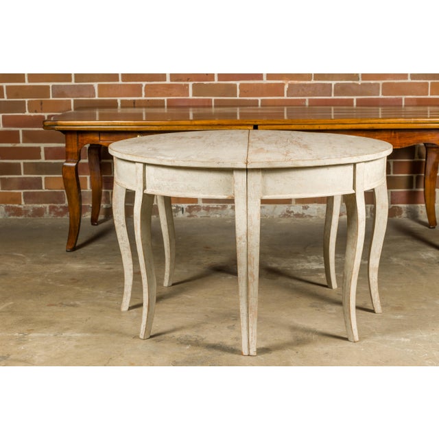A pair of Swedish Rococo style painted wood demi lune console tables from the 19th century with cabriole legs. This pair...