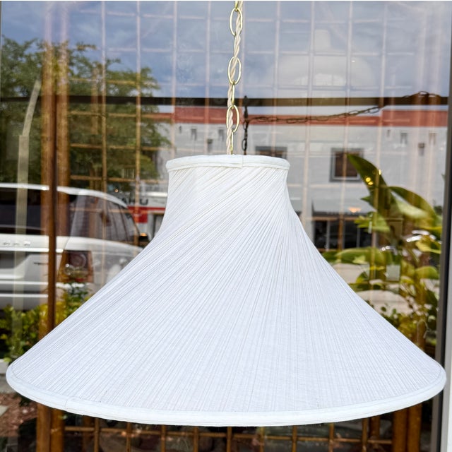 Vintage swag pendant lamp characterized by a flared, tightly pleated off-white fabric cone shade suspended from an...