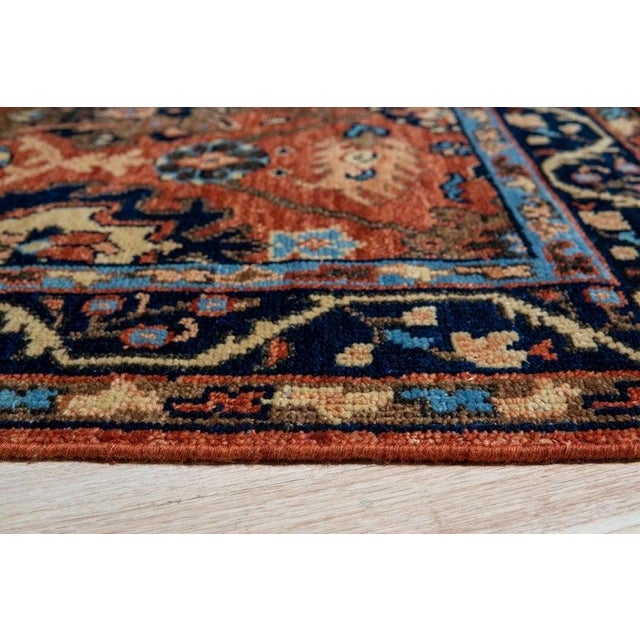 This hand knotted pile rug features a primary color palette of deep red and rust tones. Crafted from natural wool, the rug...