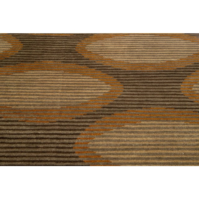 This contemporary Tufenkian rug boasts a brown abstract field. It is enriched with gray, tan, and goldenrod accents, all...