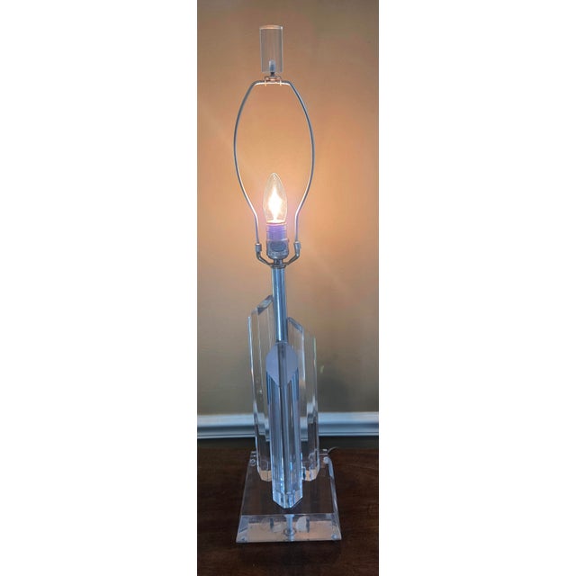 Lucite lamp with three Lucite prisms with angled tops on a Lucite base. The design reflects and refracts light. Central...
