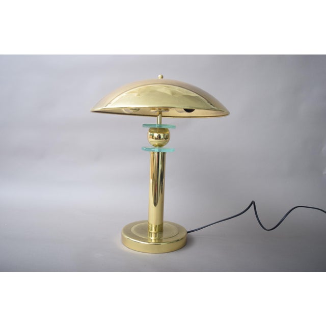 Mushroom-shaped table lamp dating to the 1990s, with a broad domed brass shade, a cylindrical brass stem and a round base....
