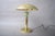 Mushroom-shaped table lamp dating to the 1990s, with a broad domed brass shade, a cylindrical brass stem and a round base....
