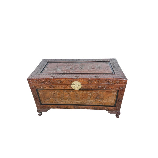 A richly decorative vintage storage chest featuring extensive carved relief work across its exterior. The chest is framed...