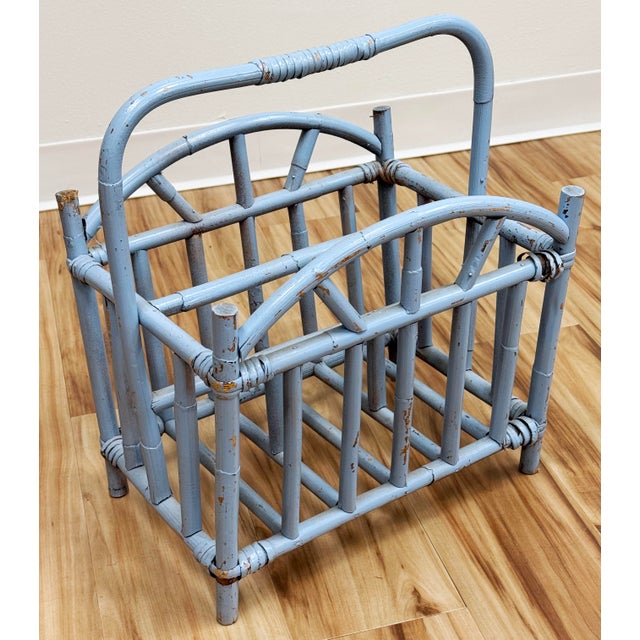 Vintage rattan magazine rack in a weathered periwinkle blue. Sturdy construction. Some unraveling to bindings as shown.