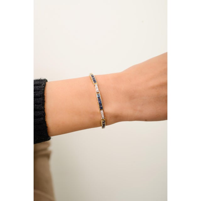 This elegant tennis bracelet features square-cut blue sapphires totaling 6.44 carats, set in rich 14k yellow gold. each...