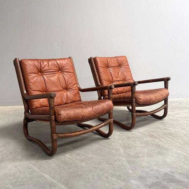 Set Danish arm chairs from the 1970s. Bamboo / manou frames with cognac leather cushions. Chairs are good condition with...