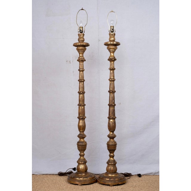 Pair of gilded wood floor lamps, custom made, late 20th century. Designs are hand carved and gilded. Light bulbs and harps...