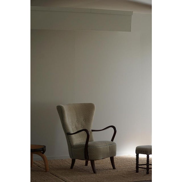 Presenting a stunning lounge chair with matching footstool from the 1960s, expertly crafted in beech and with original...