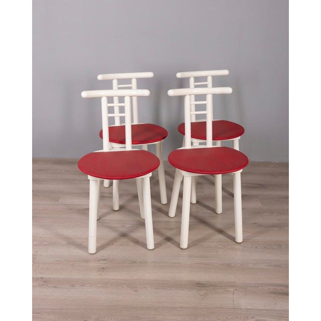 Set of four chairs in white lacquered wood with red vinyl seat, Italian design, 1980s.