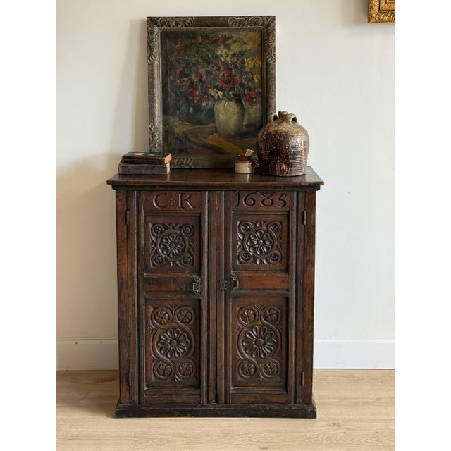 A late 17th-century English oak cupboard dated 1685, carved with the initials “C R” for Charles Regina, marking the reign...