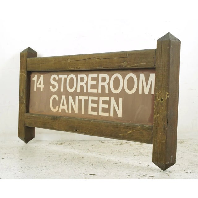Reclaimed storeroom canteen outdoor sign made of a rectangular plastic center and wood posts. The sign reads, "14...