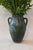 This handled Mediterranean vase features a warm terracotta finish with a darker, textured glaze around the neck and...