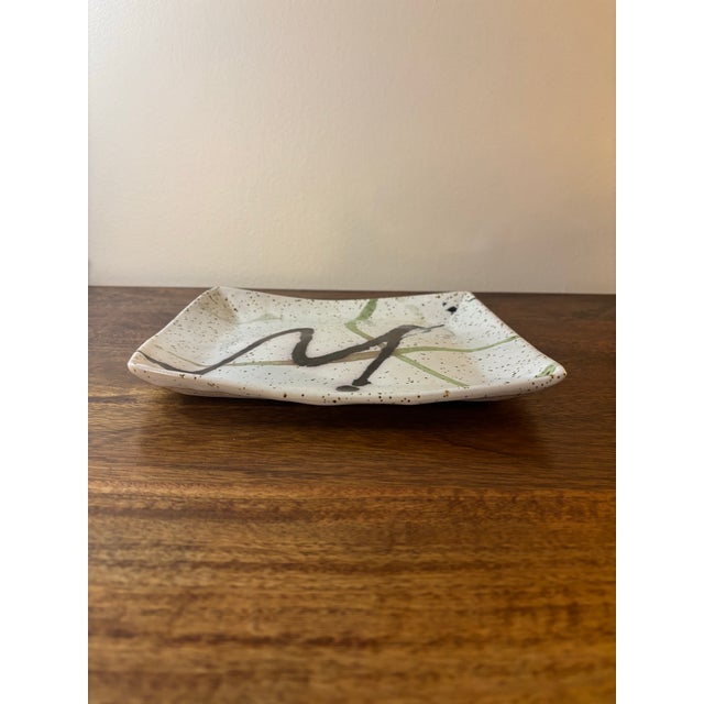 A beautifully composed vintage mid-century era studio pottery decorative plate with a softly bulbous square form and...
