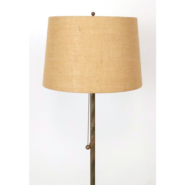 Mid Century style table floor lamp made of a brass stem, aluminum base, travertine table tray, and a burlap shade. It is...