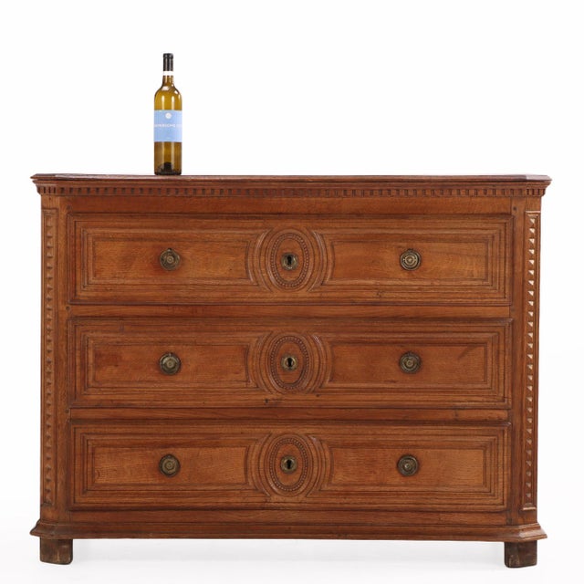 A distinguished late 18th-century French commode crafted in solid oak, featuring a rectangular case with elegantly canted...